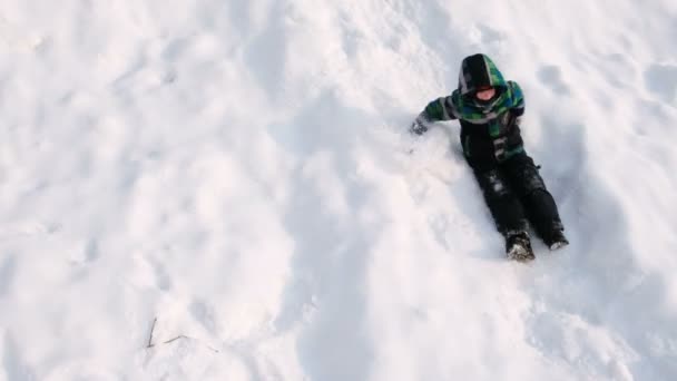 Le garçon descend la montagne enneigée et court vers l'avant. Vue latérale . — Video