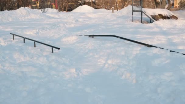 Skatepark stravování v zasněžené zimní city parku. Sněhové závěje na kopci na skateboardu. — Stock video