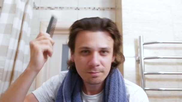 Shaggy mladík češe vlasy s hřebenem po tom hlava praní. — Stock video