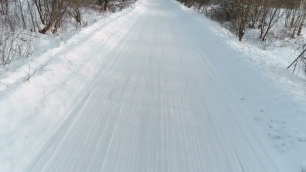 Camino de invierno cubierto de nieve, imágenes aéreas. Cámara movimiento hacia atrás . — Vídeo de stock