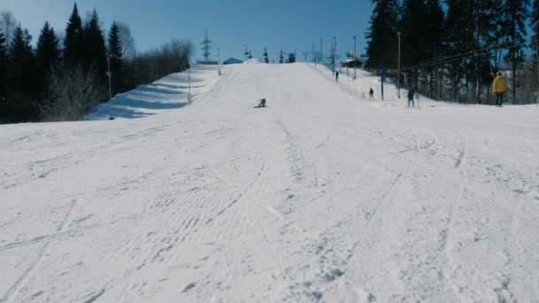 12岁的十几岁的男孩穿着灰色西装从雪下降的滑雪板上滑行下天空电梯。从远处看. — 图库视频影像