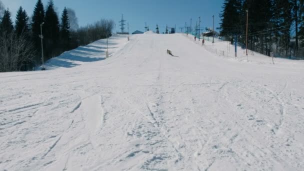 Ο άνθρωπος σε κίτρινο σακάκι συρόμενη σε ένα snowboard από χιόνι καθόδου επόμενο ουρανός ανελκυστήρα στο Δημοτικό Πάρκο. — Αρχείο Βίντεο