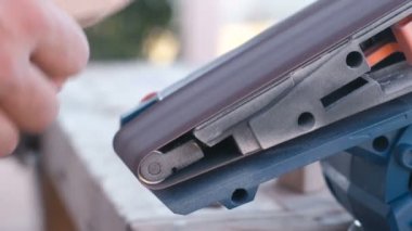 Marangoz öğütme makinesinde ahşap parçalar parlatır. Eller yakın çekim..