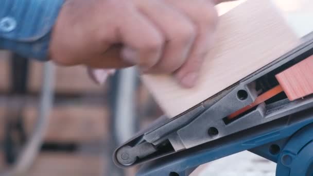 Timmerman polijst een houten delen van speelgoedauto op een slijpmachine. Close-up handen. — Stockvideo
