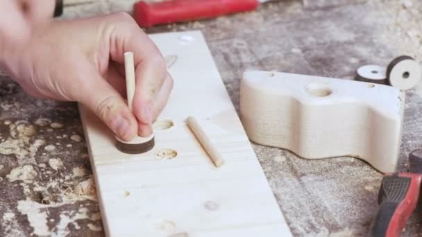 Worker recoge una máquina de madera de juguete de varias partes. Mano de primer plano . — Vídeos de Stock