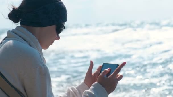 Vrouw foto's van de zee en de golven die zittend op de oever. — Stockvideo