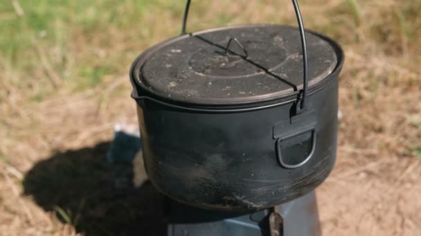 Pot on a metal camp furnace stove on woods outdoors. Close-up. — Stock Video