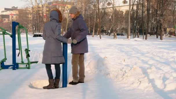 Άνδρας και γυναίκα σε μπλε μπουφάν είναι ασχολούνται με προσομοιωτές και μιλώντας στο χειμερινό πάρκο. Πλάγια όψη. — Αρχείο Βίντεο