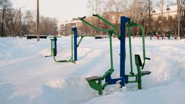 Fitnessgeräte für den Sport, schneebedeckt im winterlichen Stadtpark. — Stockvideo