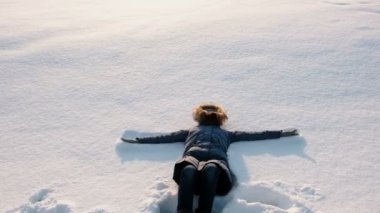 Kadın mavi ceket kürk başlık ile aşağı bir kar melek yapar.