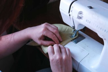 Kadın bir dikiş makinesi diker. Eller yakın çekim.