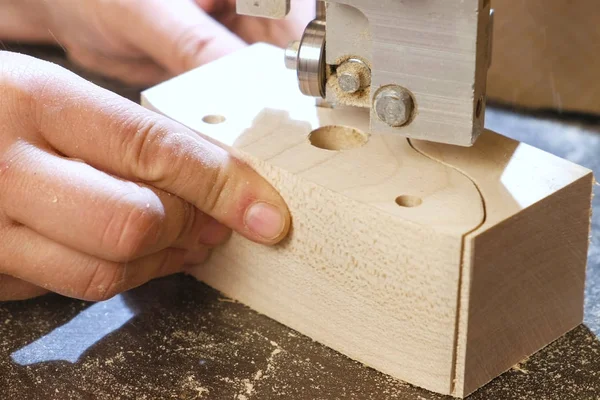Handwerker sägt mit der Bandsäge ein Werkstück für Spielzeugautos aus Holz. Hände aus nächster Nähe. — Stockfoto