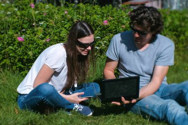 Genç çift erkek ve kadın birlikte parkta oturan laptop ve cep çalışıyoruz.