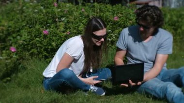 Genç çift erkek ve kadın birlikte parkta oturan laptop ve cep çalışıyoruz.