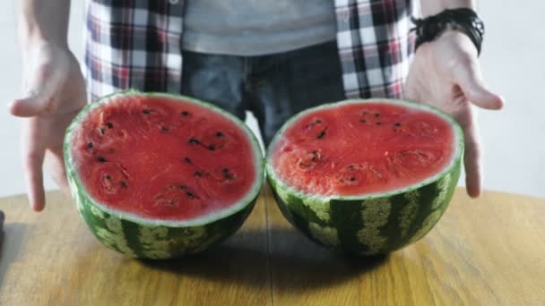 Člověk zkoumá meloun nakrájíme na dvě poloviny na kuchyňském stole. Detail ruce. — Stock video