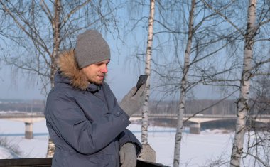 Ceket kürk kız kış parkta sohbet video için cep telefonu kullanarak ile aşağı mavili adam.