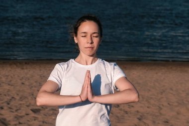 Şehrin nehir kenarında kumsalda Yoga esneme kadın. Güzel bir şehir manzarası. Namaste poz.