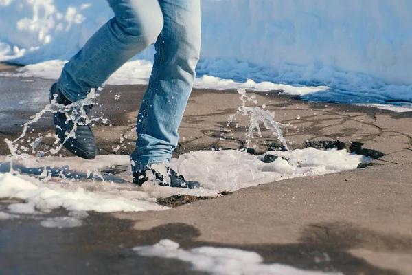 L'homme tombe dans une flaque de neige dans l'asphalte avec son pied. Gros plan jambes . — Photo