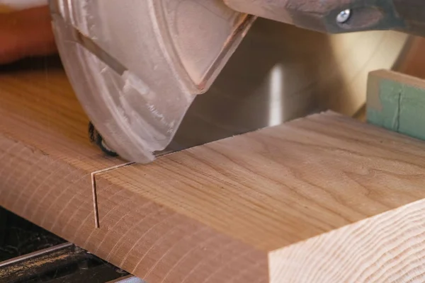 Trabajador aserrando una tabla de madera con una sierra circular. Primer plano de las manos . — Foto de Stock