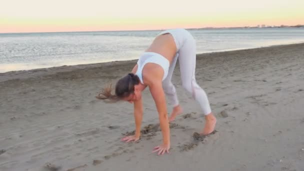 Junge Frau beim Yoga am Sandstrand bei Sonnenaufgang. Plankenpose. — Stockvideo