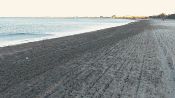 Lidé jsou běhání na písčité pláži u moře při západu slunce v podzimní, zadní pohled. — Stock video