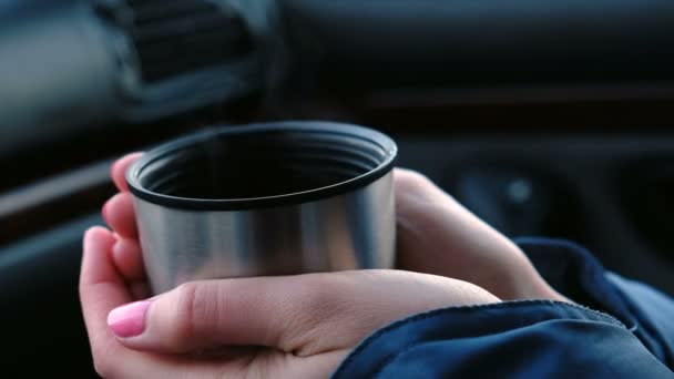 El primer plano de una taza de té caliente de un termo en las manos de una mujer en el coche en invierno . — Vídeo de stock