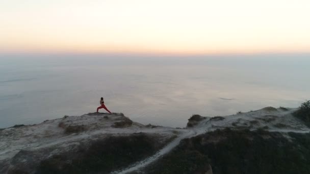 Femme s'étend sur le sommet de la montagne avec vue sur la mer au coucher du soleil. Des images aériennes. Vue latérale . — Video