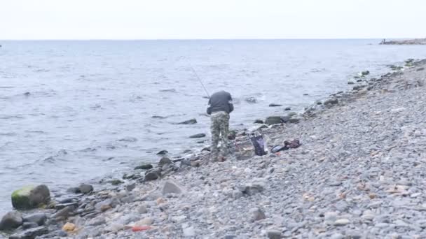 Невідомий чоловік рибальський стрижень на морському пляжі . — стокове відео