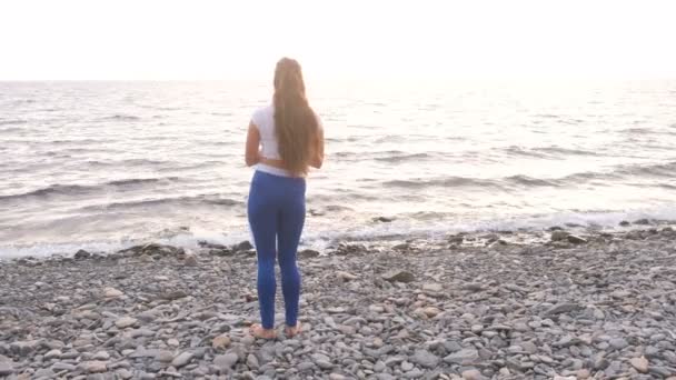 Girl is doing exercise lunge, leg lift the bodyflex during breathing exercises on the sea background. — Stock Video