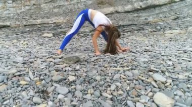 Kadın yoga ve rock ve deniz arka plan üzerinde fiziksel egzersizler yapıyor. Hava güzel görüntüleri görünümü.