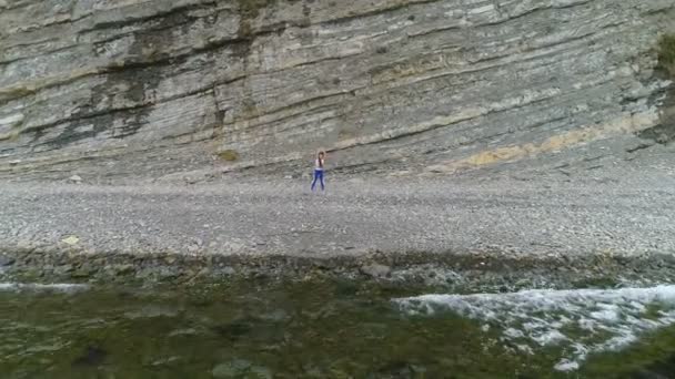 Frau macht Yoga und körperliche Übungen auf Felsen und Meer Hintergrund. Luftaufnahme schöner Aufnahmen. — Stockvideo