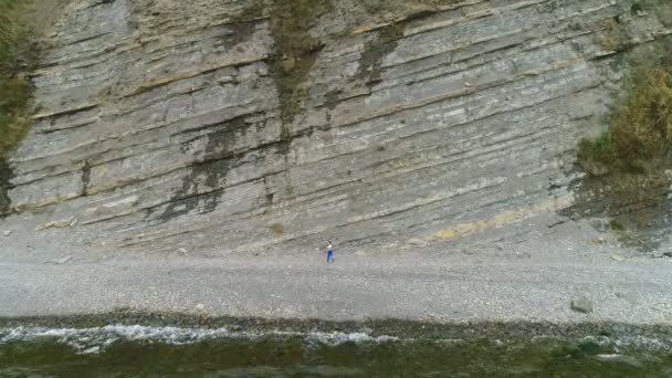 Vrouw doet yoga en fysieke oefeningen voor de benen op rock achtergrond. Luchtfoto mooi beeldmateriaal bekijken. — Stockvideo