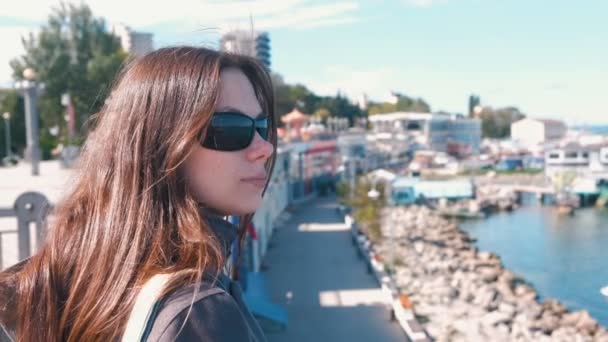 Giovane donna bruna in occhiali da sole guardando il mare in autunno . — Video Stock