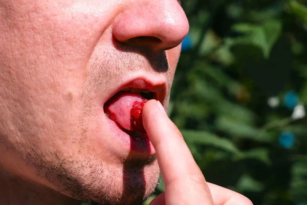 Man eats raspberries, mouth close up outdoor. — Stock Photo, Image