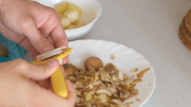 Mans hands is peeling potato with yellow peeler. — Stock Video