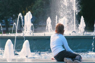 Oğlan çeşmede güneşli bir günde görünüyor..