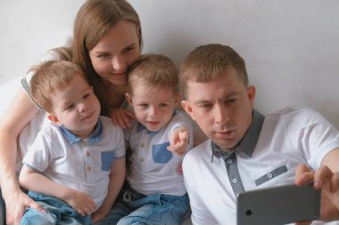 Baba aile selfie üstünde hareket eden telefon ediyor. Anne, baba ve iki kardeş ikiz bebekler.