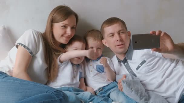 Vader maakt familie selfie op mobiele telefoon. Moeder, vader en twee broer twins peuters. — Stockvideo