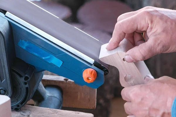 Tischler poliert ein Holzteil auf einer Schleifmaschine. Hände aus nächster Nähe. — Stockfoto