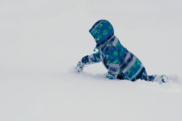 Αγόρι σέρνεται κλίσεις χιονιού και σκάβει στο χιόνι. — Φωτογραφία Αρχείου