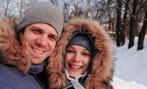 Paar unterhält sich über Videoverbindung und Spaziergang im winterlichen Stadtpark an einem verschneiten Tag mit fallendem Schnee. — Stockfoto
