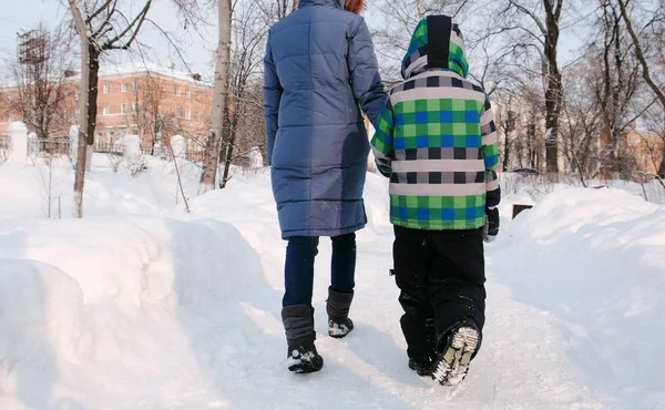 Mamá e hijo caminando en el parque de la ciudad de invierno. Vista trasera . — Foto de Stock