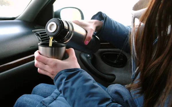 Close-up mulheres mãos derramando um chá quente em uma xícara de garrafa térmica no carro no inverno . — Fotografia de Stock