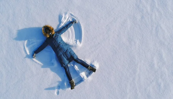Женщина заставляет снежного ангела лежать в снегу. Вид сверху. Аэрофотосъемка . — стоковое фото