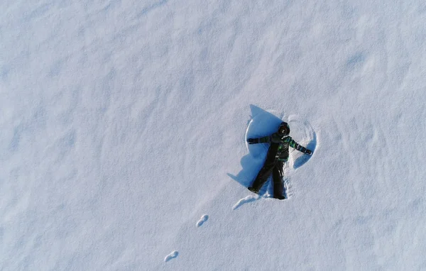 Garçon de 7 ans fait ange de neige dans la région de la neige. Photo aérienne . — Photo
