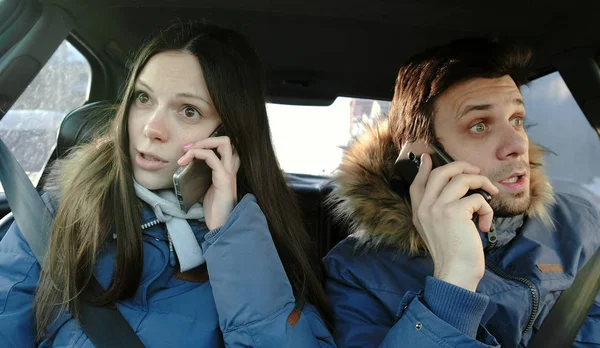 Homem e mulher jurando seus celulares sentados no carro . — Fotografia de Stock