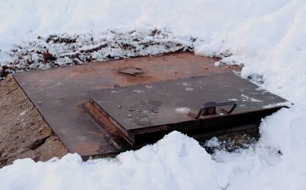 Steam is from sanitary sewer cover in snow, Melted snow around. Close-up view. — Stock Photo, Image