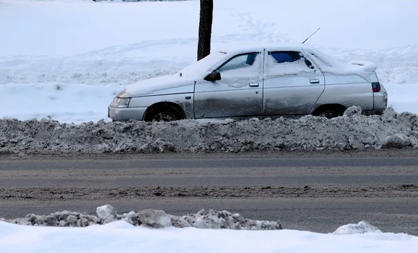 雪に覆われた道の端に雪に覆われた車。横から見た図. — ストック写真