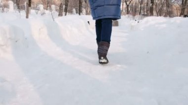 Closeup kadının bacakları dolaşıyor şehrin parkında kış sırasında düşen kar ile karlı havalarda günde. Yan görünüm.