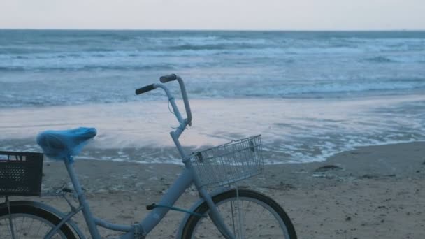 Bicicleta velha na praia ao pôr do sol com mar tempestade e fundo ondas de espuma . — Vídeo de Stock